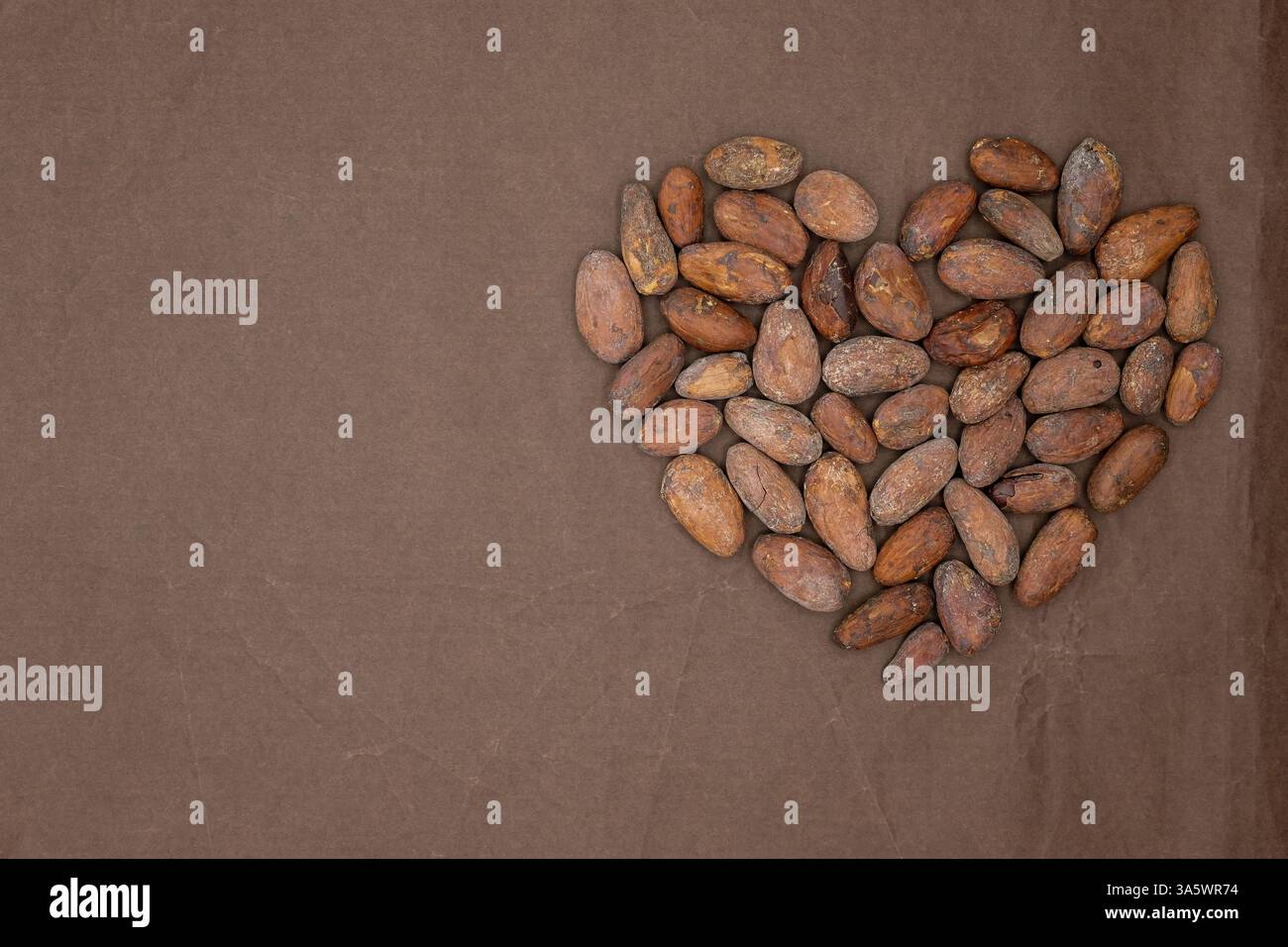 Le coeur est conçu à partir de fèves de cacao dans la tendance de couleur Mocha mousse 2025 chaude. Fond de papier de soie de couleur chocolat. Copier l'espace. Banque D'Images