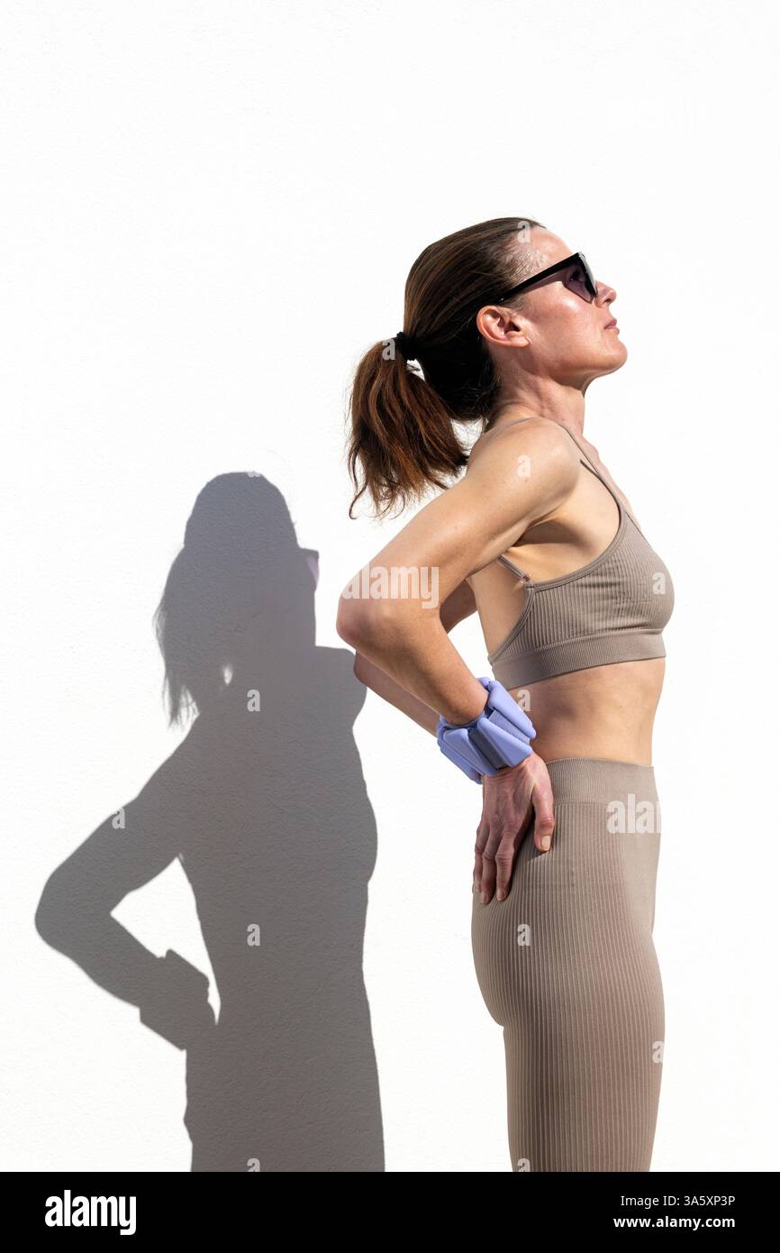 fit femme sportive étirant avec poids de poignet réglables, à l'extérieur Banque D'Images