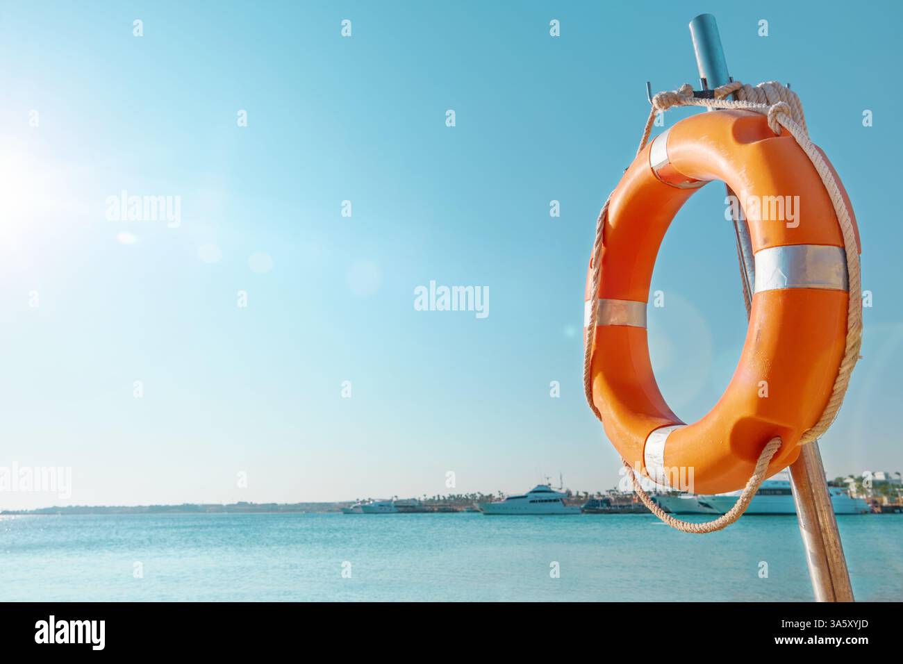 Cercle de bouées de sauvetage. Vue panoramique de bouée de sauvetage rouge et blanche sur le poteau sur la plage de bord de mer. Paysage de paysage de la rive de l'océan de mer le jour ensoleillé. Dispositif de sauvetage en eau Banque D'Images