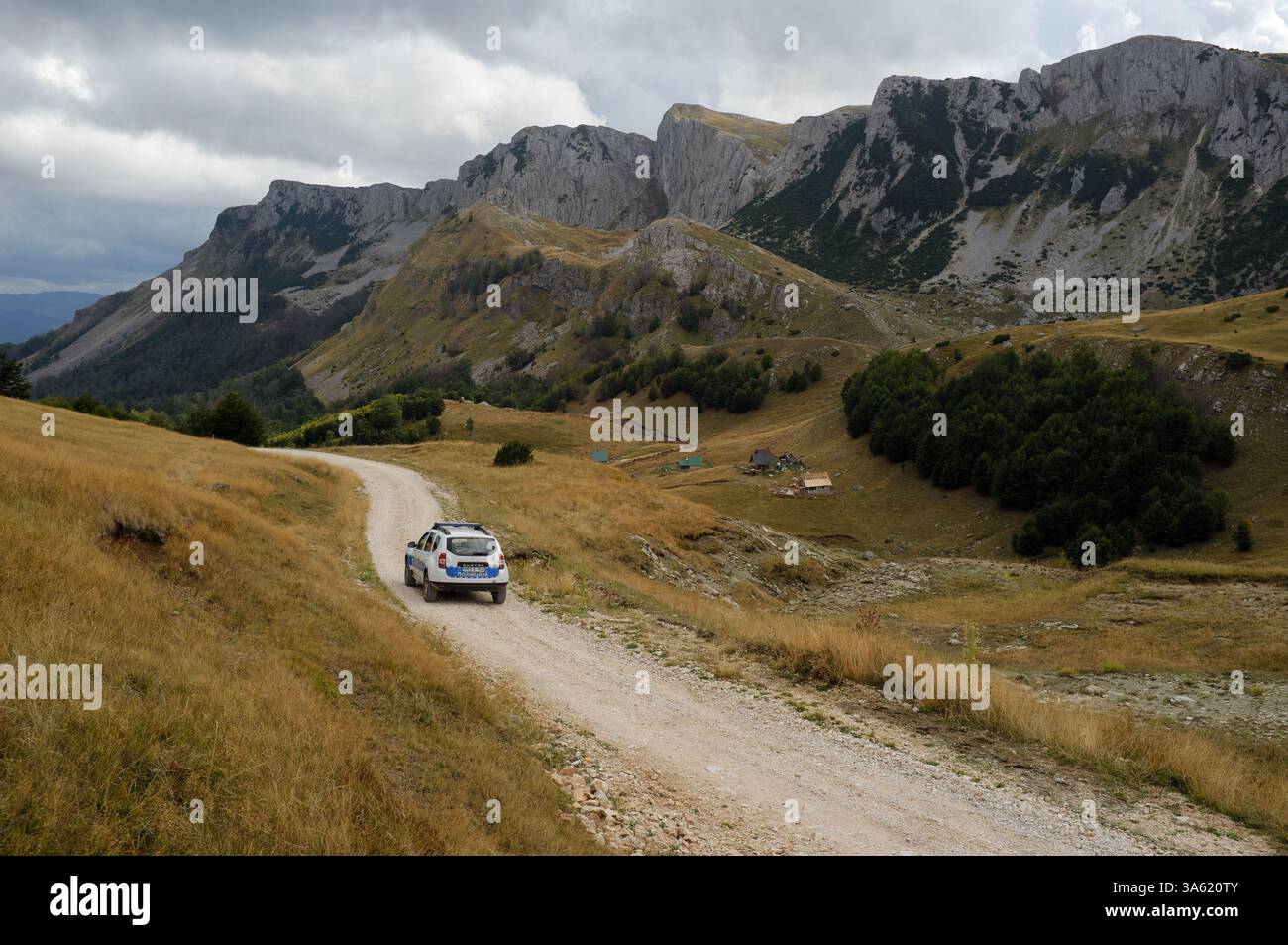 Voiture de police conduite sur la route de terre à travers la chaîne de montagnes des Alpes dinariques jusqu'au lac Orlovacko dans le parc national de Sutjeska, Bosnie-Herzégovine Banque D'Images