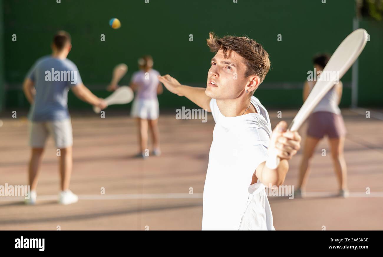 Jeune homme joueur de pelote frapper balle avec raquette en bois Banque D'Images