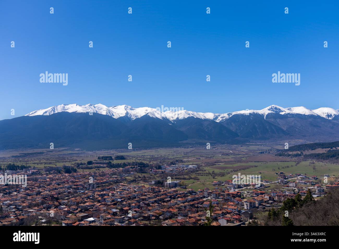 Vue panoramique capturant la vallée de Razlog et la majestueuse montagne Pirin, mettant en valeur des sommets enneigés dans un ciel bleu clair en Bulgarie Banque D'Images