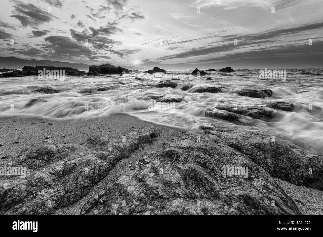 Gros plan sur un grand angle d'Une vague roulant sur le rivage qui coule au-dessus de Sea Rocks dans Une image spectaculaire en noir et blanc à contraste élevé Banque D'Images