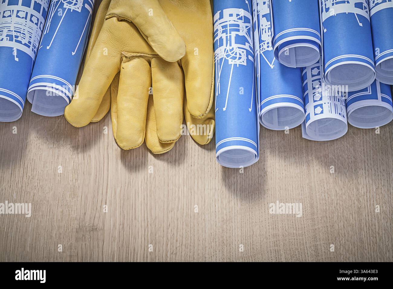Gants de protection en cuir bleus roulés plans de construction sur panneau de bois Banque D'Images