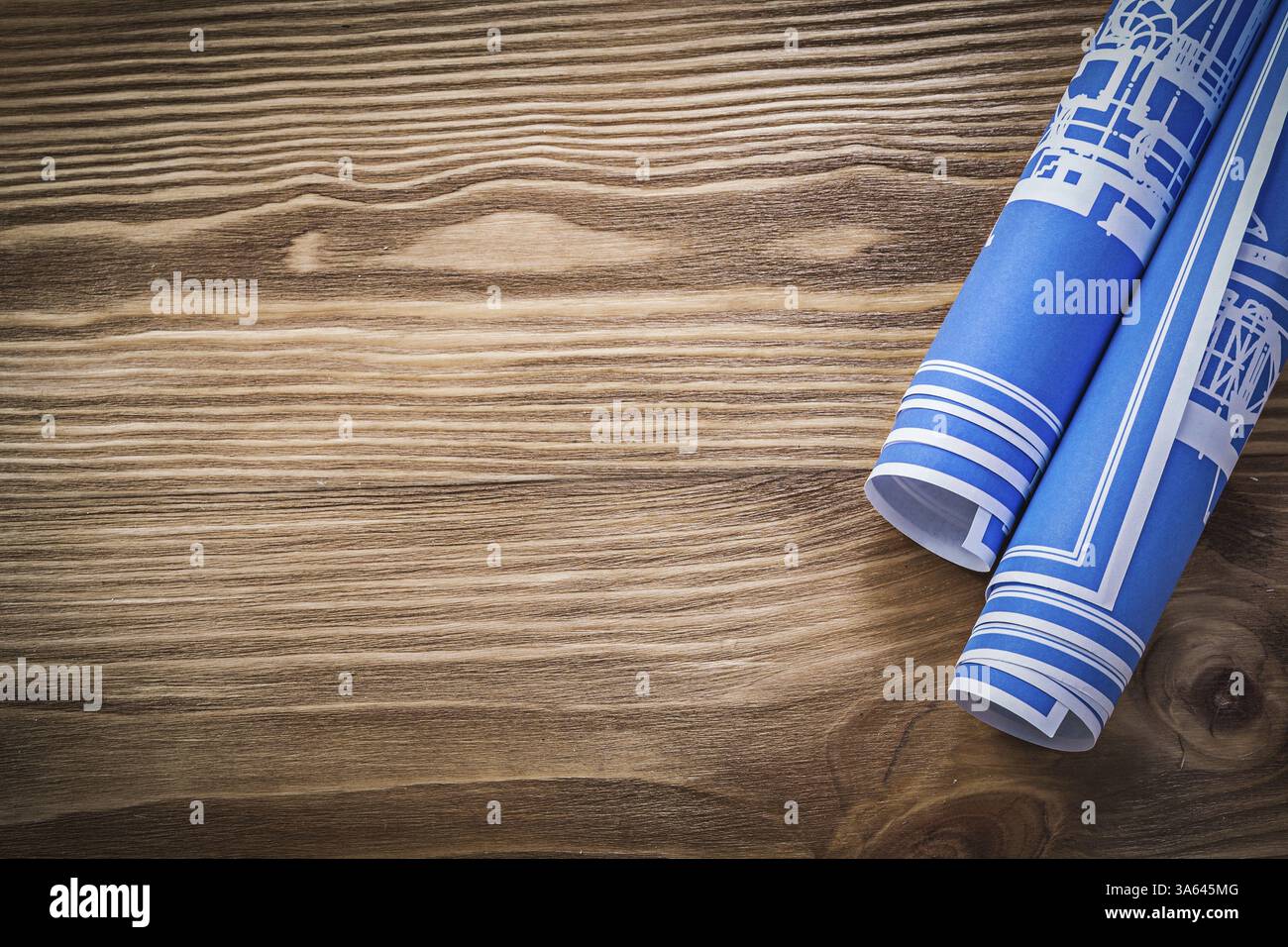 Plans de construction roulés bleus sur l'espace de copie de planche en bois Banque D'Images