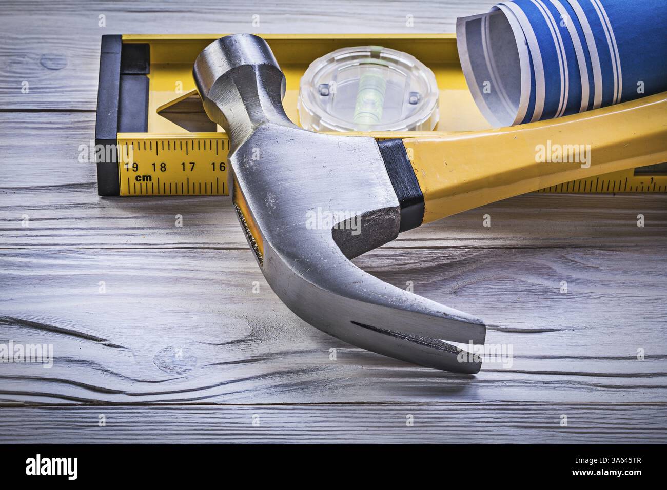 Marteau à griffes bleu dessins d'ingénierie roulés niveau de construction sur planche de bois Banque D'Images