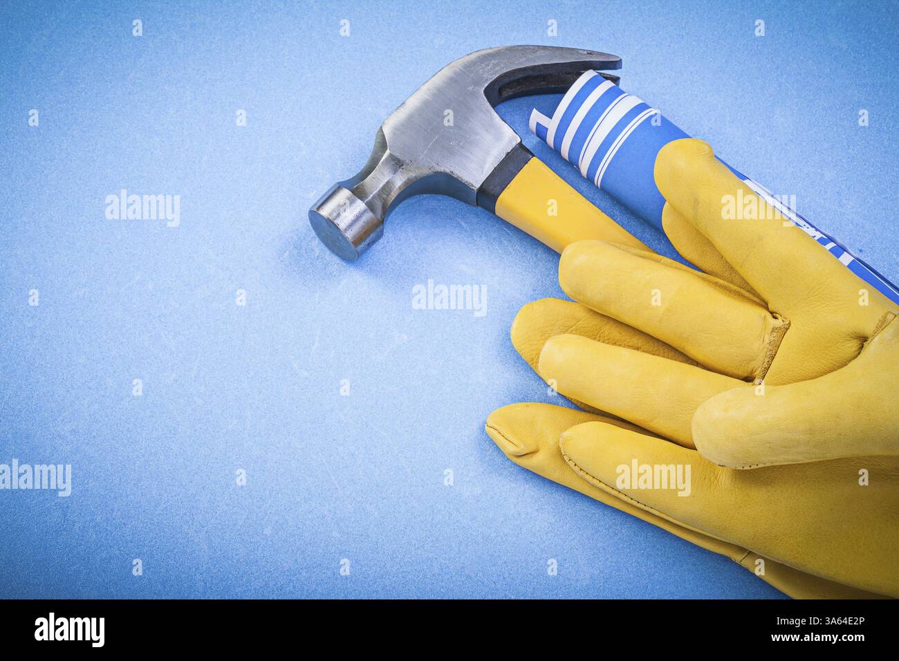 Gants de protection de marteau à griffes plans de construction roulés sur fond bleu Banque D'Images