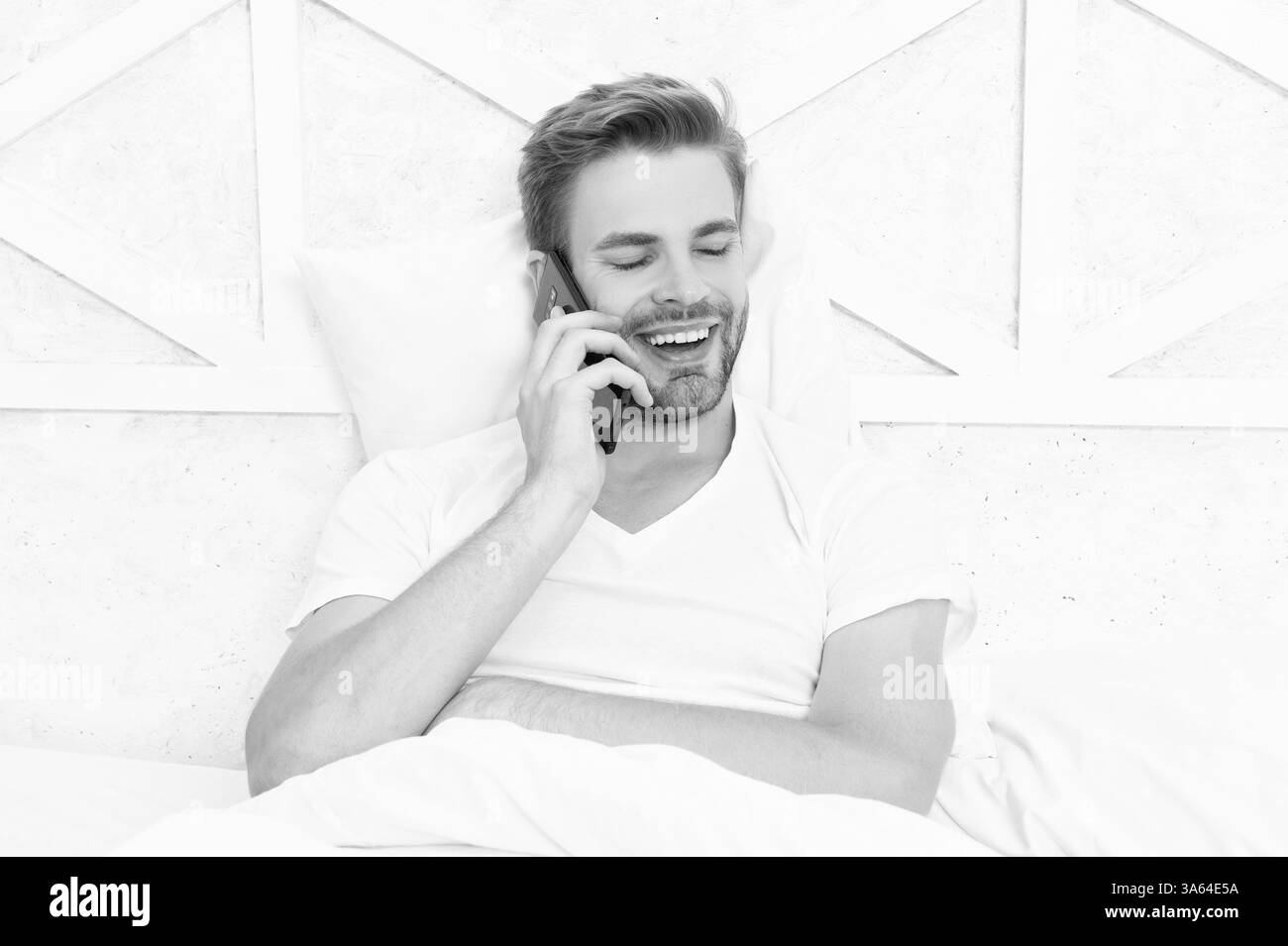 Jeune homme au lit ayant une conversation téléphonique. Appel téléphonique. Homme avec smartphone dans le lit. Communication avec smartphone. L'homme millénaire utilise un smartphone dans la chambre Banque D'Images