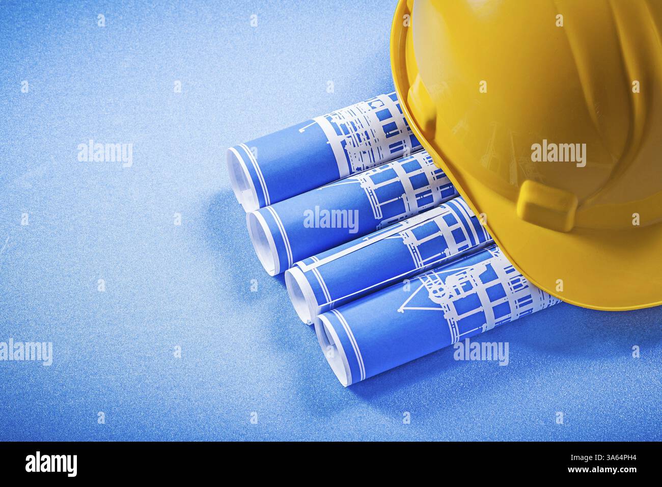 Casquette roulée de plans de construction sur fond bleu Banque D'Images
