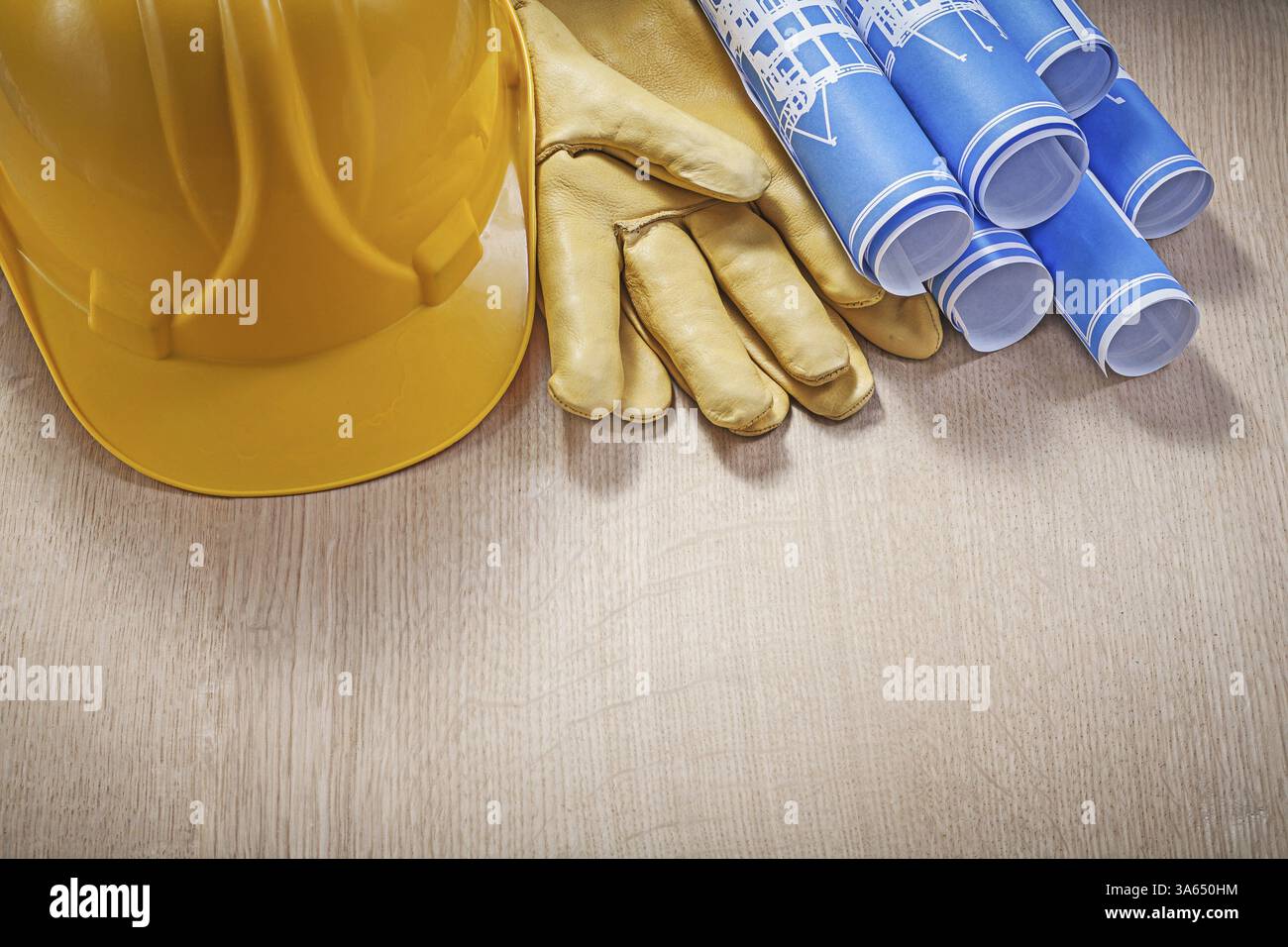 Dessins de construction roulés bleus construction casque gants de protection en cuir sur planche de bois Banque D'Images