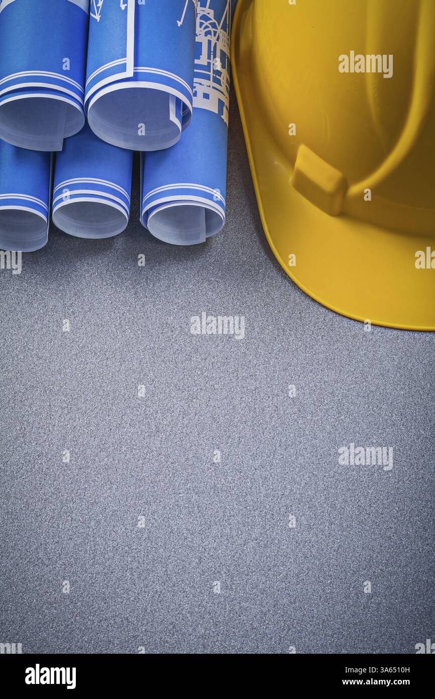 Casque de construction bleu roulé vers le haut des dessins de construction sur fond gris Banque D'Images
