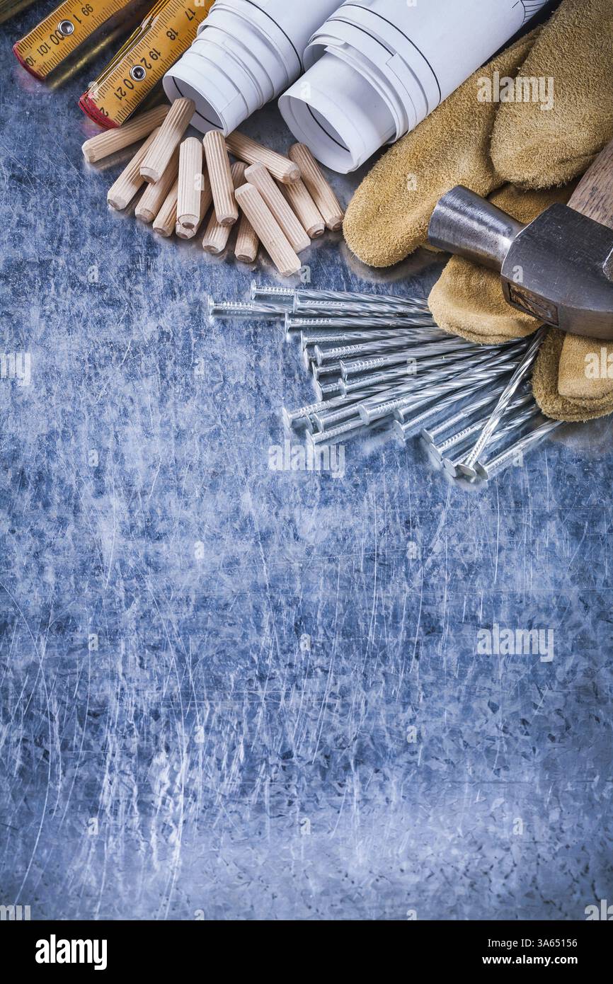 Blueprints gants de protection marteau en bois clous de construction de mètre et pile de chevilles sur le concept d'entretien de surface métallique rayée Banque D'Images