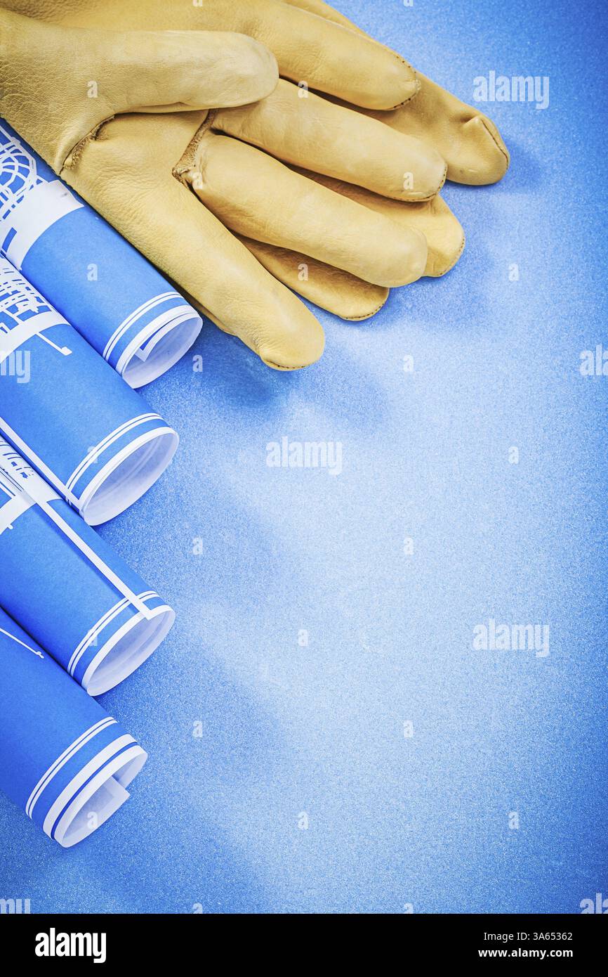 Dessins d'ingénierie enroulés gants de protection sur fond bleu concept de construction Banque D'Images