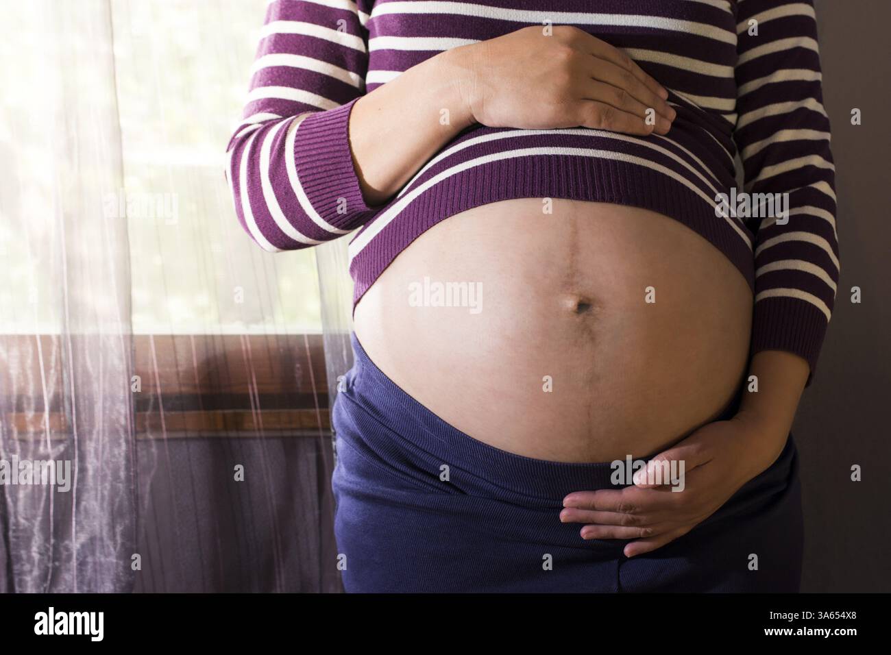 Les femmes enceintes à la fenêtre. Couleurs violet Banque D'Images