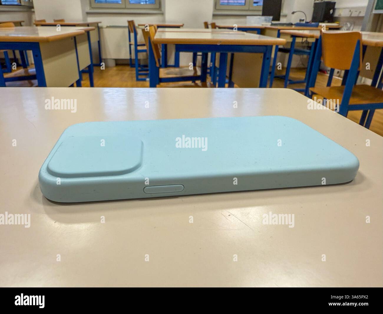 Smartphone laissé sur le bureau dans une salle de classe vide – concept d'interdiction de téléphone Banque D'Images