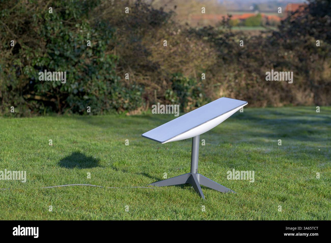 Antenne parabolique sur un terrain d'herbe avec des arbres et un fond pittoresque ; innovation technologique permettant la connectivité. Idéal pour mettre en évidence les avancées Banque D'Images