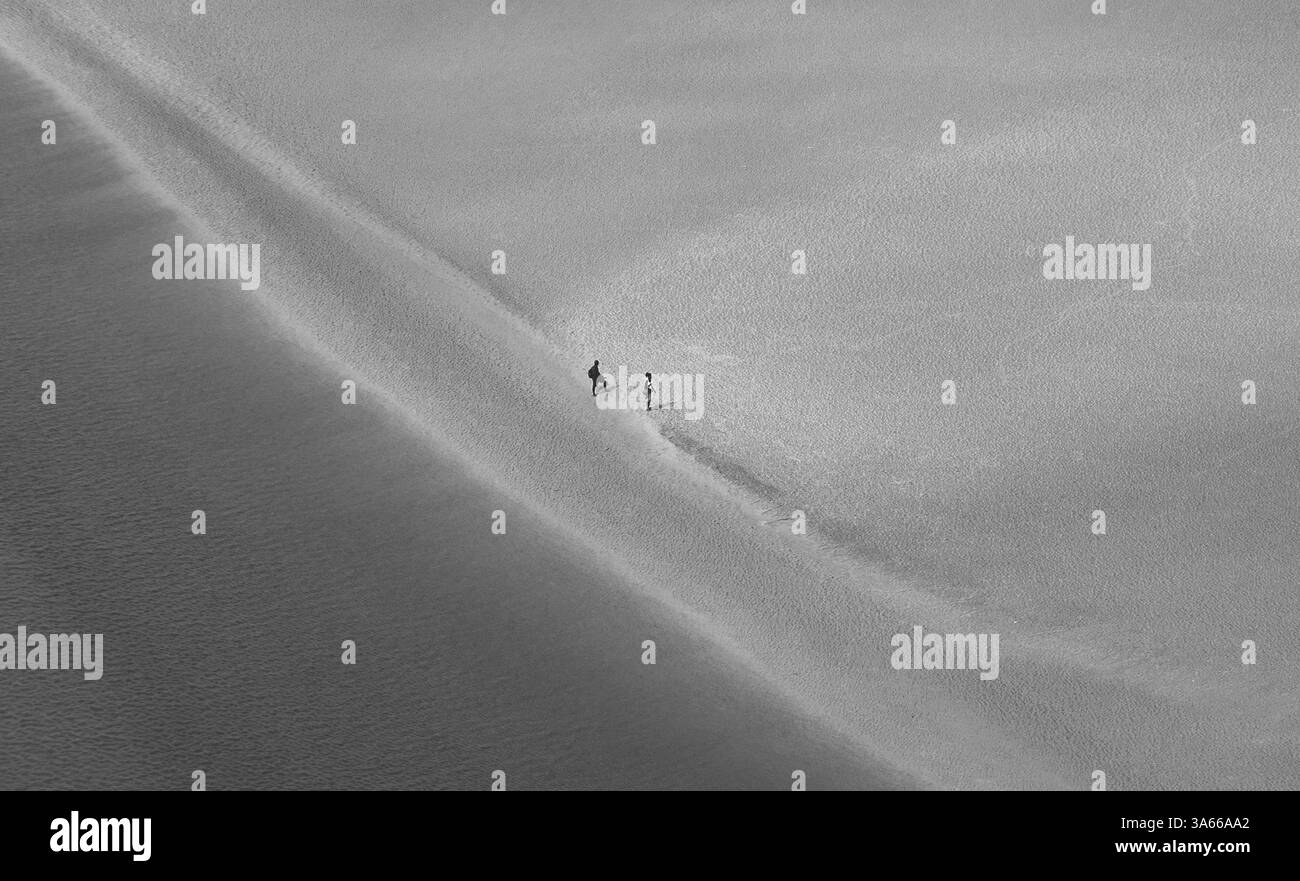 Paysage avec l'embouchure de la rivière vue du Mont Saint Michel et couple méconnaissable marchant à marée basse fond de l'océan loin. Liberté, peu de pers Banque D'Images