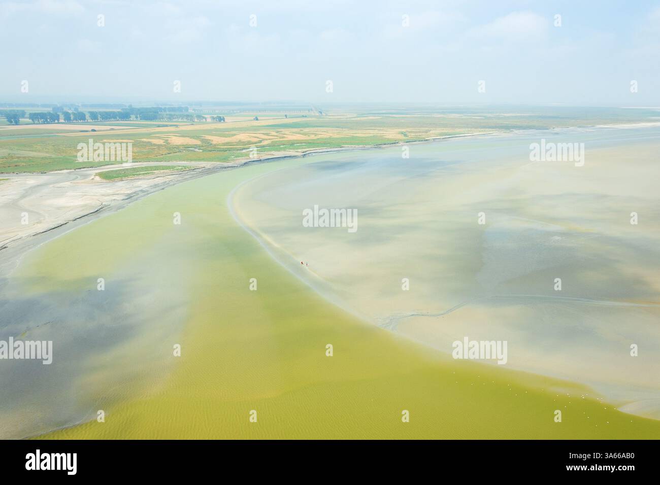 Paysage avec l'embouchure de la rivière vue du Mont Saint Michel et couple marchant à marée basse fond de l'océan loin. La liberté, la petite personne humaine dans le monde Banque D'Images