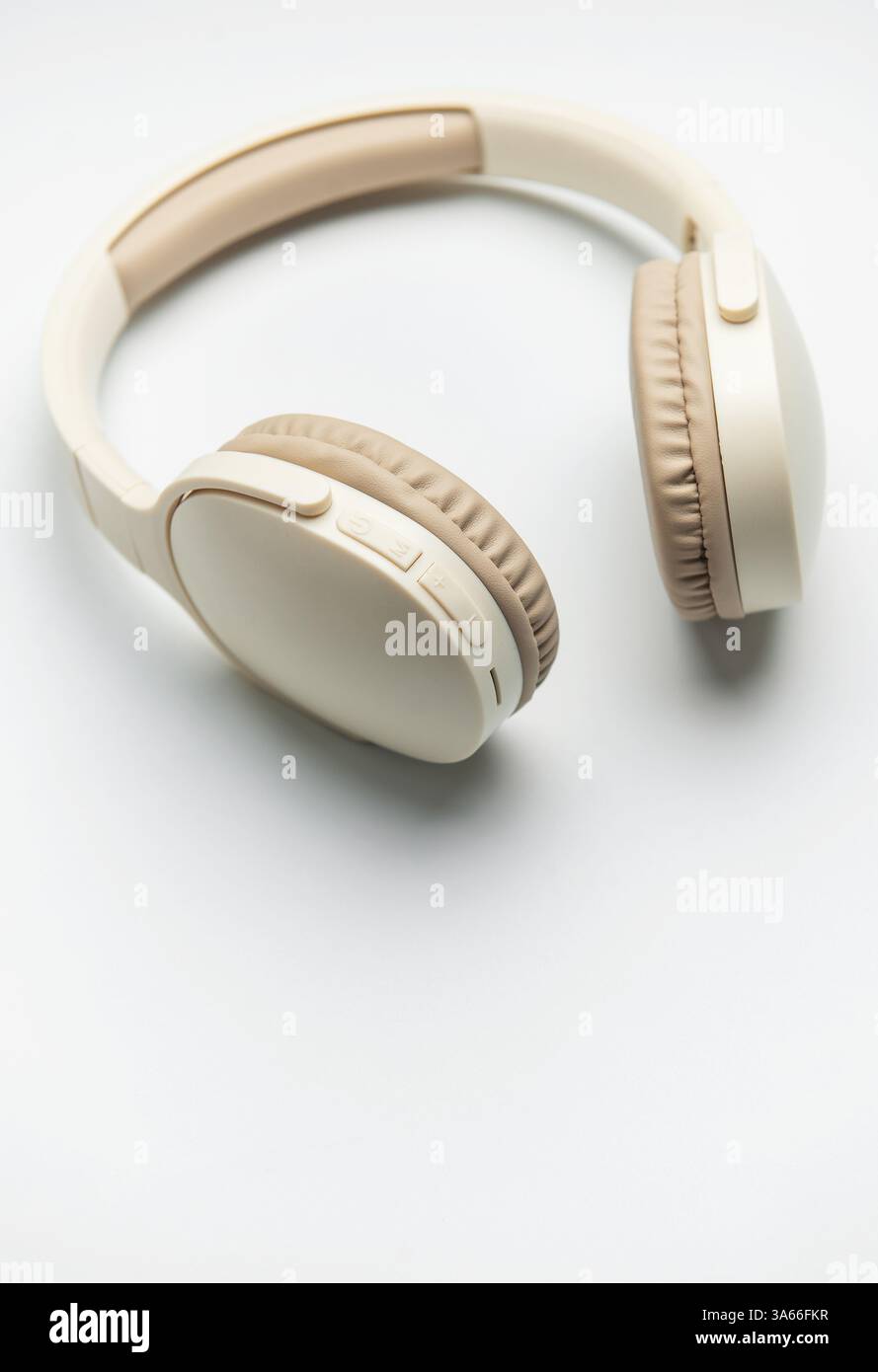 Casque sans fil beige et blanc isolé sur fond blanc, représentant l'écoute de musique, le plaisir de podcast ou la communication audio Banque D'Images