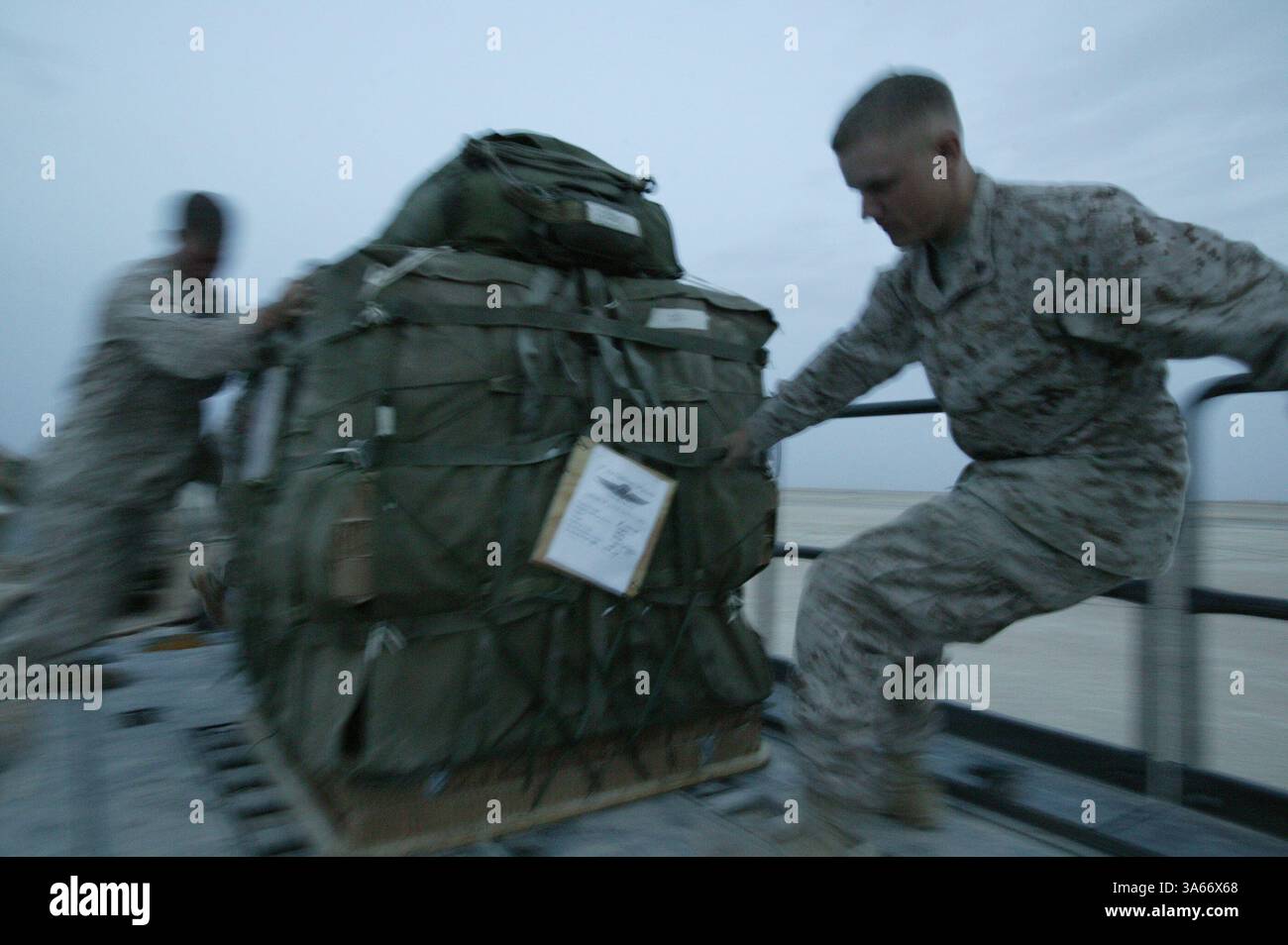 Le 19 mai 2004 ; Camp Al Asad, Irak ; le Cpl CHRIS M. KADOLPH, à droite, et le Cpl DOUGLAS F. MILLER, gréeurs de parachutistes du peloton de livraison aérienne, bataillon de soutien des services de combat 7, déplacent une palette de fret au Camp Al Asad, Irak, le 19 mai 2004. Seize palettes chargées de 22 000 livres de nourriture et d'eau ont été larguées sur des Marines opérant dans l'ouest de l'Irak le 20 mai 2004. La mission était le premier largage d'approvisionnement aérien de combat effectué depuis le retour des Marines en Irak cette année. CSSB-7 fait partie du Groupe de soutien des services de la 1re Force. Kadolph, 21 ans, est originaire de Jackson, Wisconsin. Miller, 20 ans, est originaire de Santa Rosa, Calif. Banque D'Images