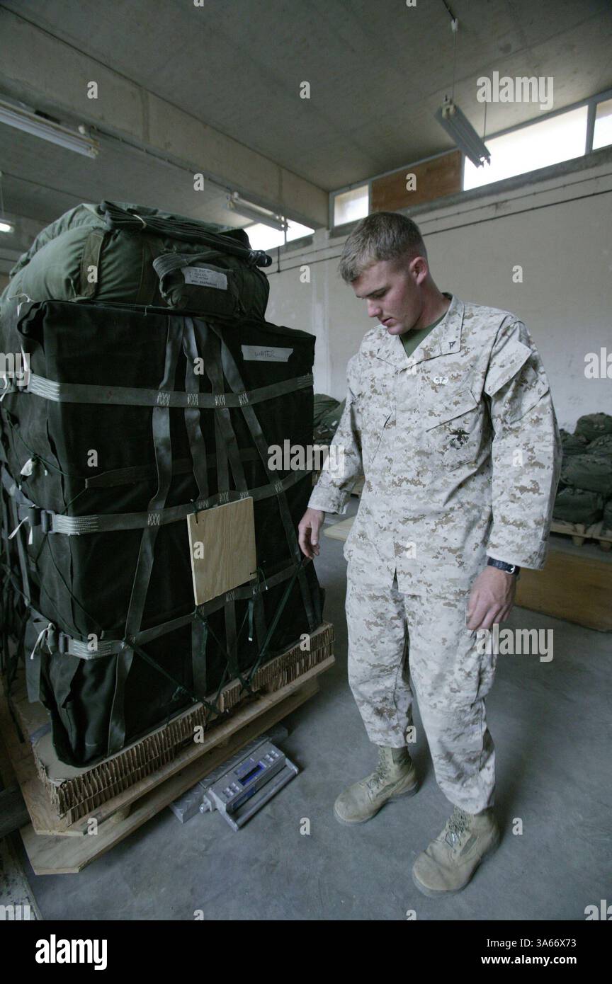 19 mai 2004 ; Camp Al Asad, Irak ; lance le Cpl DOUGLAS F. MILLER, gréeur de parachutistes du peloton de livraison aérienne, bataillon de soutien des services de combat 7, pèse une palette de fret avant de la charger dans un avion au Camp Al Asad, Irak, le 19 mai 2004. Seize palettes chargées de 22 000 livres de nourriture et d'eau ont été larguées sur des Marines opérant dans l'ouest de l'Irak le 20 mai 2004. La mission était le premier largage d'approvisionnement aérien de combat effectué depuis le retour des Marines en Irak cette année. CSSB-7 fait partie du Groupe de soutien des services de la 1re Force. Miller, 20 ans, est originaire de Santa Rosa, Calif. Banque D'Images