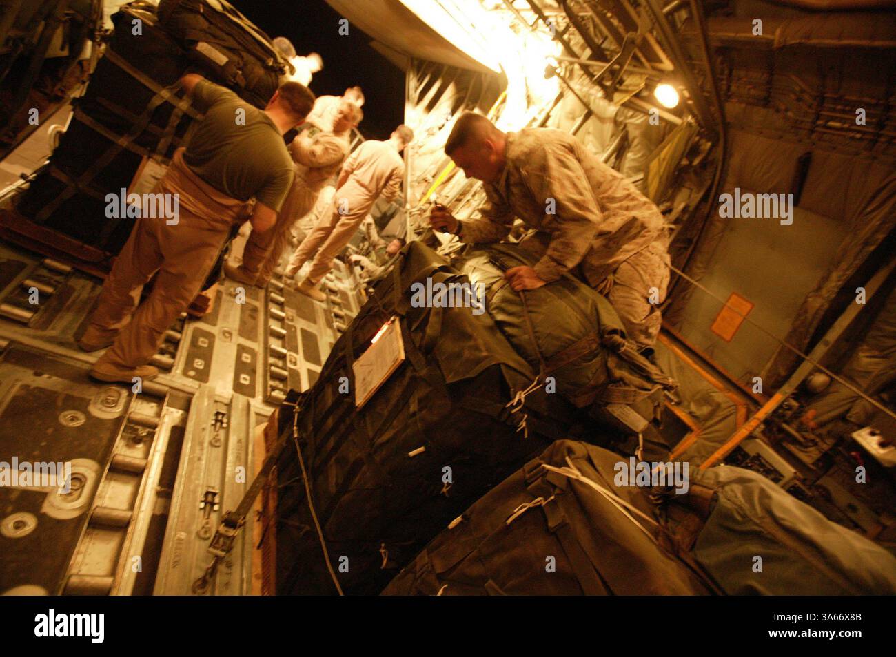 19 mai 2004 ; Camp Al Asad, Irak ; gréeurs de parachute avec peloton de livraison aérienne, bataillon de soutien des services de combat 7, chargent des palettes de fret et inspectent leurs sangles de gréement de parachute dans la soute d'un avion KC-130 au Camp Al Asad, Irak, le 19 mai 2004. Seize palettes chargées de 22 000 livres de nourriture et d'eau ont été larguées sur des Marines opérant dans l'ouest de l'Irak le 20 mai 2004. La mission était le premier largage d'approvisionnement aérien de combat effectué depuis le retour des Marines en Irak cette année. CSSB-7 fait partie du Groupe de soutien des services de la 1re Force. Banque D'Images