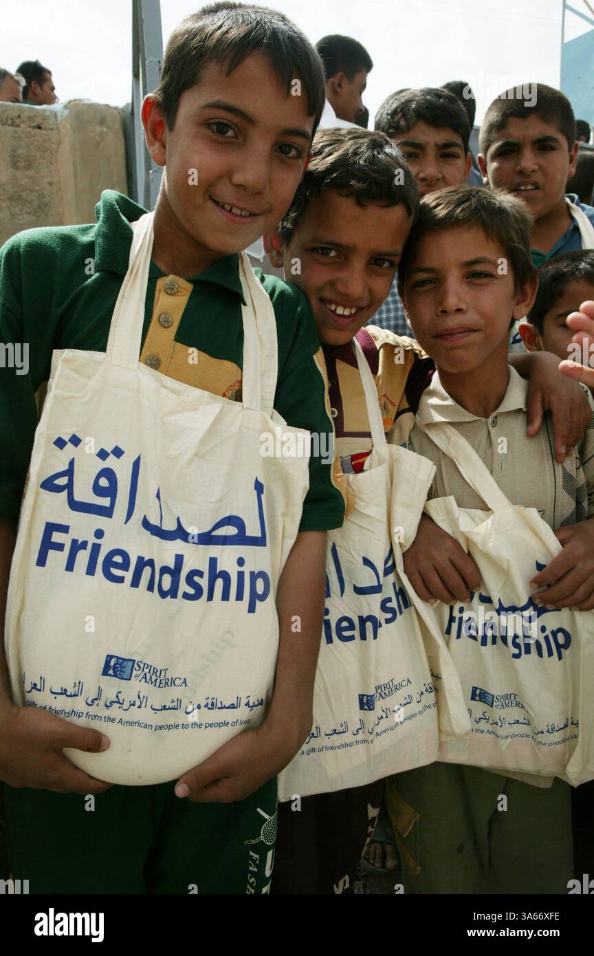 22 mai 2004 ; Kharma, Irak ; trois élèves d'une école Kharma montrent leurs nouveaux sacs de livres qui leur ont été donnés lors d'une visite de l'équipe du 3e Groupe des affaires civiles sous le 1er Bataillon du 5e Régiment de Marines le 22 mai. L'école est l'une des onze écoles qui ont reçu de l'aide de Marines comme de la peinture neuve, des portes et des fenêtres. Spirit of America, une organisation à but non lucratif basée à Los Angeles, a parrainé le bataillon avec plus de 1 500 sacs à livres, fournitures scolaires et médicales et jouets. Banque D'Images