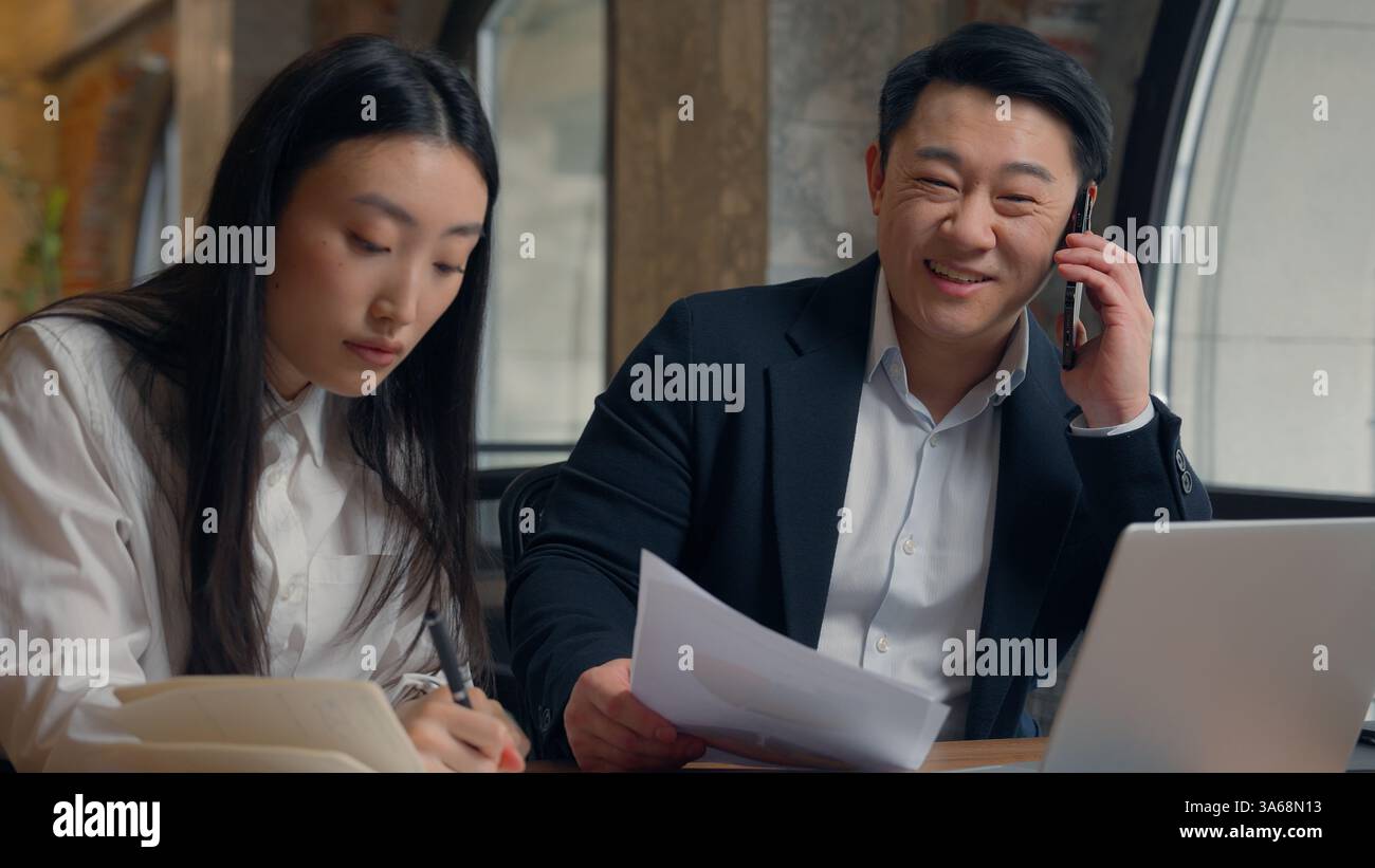 Deux directeurs d'entreprise collègues des collègues asiatiques travaillent ensemble des documents de travail d'équipe analysent la femme chinoise fille femme d'affaires japonaise homme coréen Banque D'Images