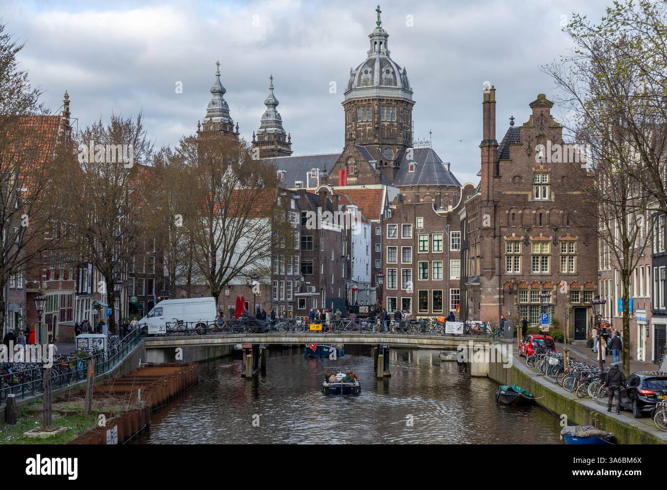 Basilique Saint-Nicolas avec canal à Amsterdam. Vélos et bateaux sur le paysage de rue par une journée nuageuse. Banque D'Images