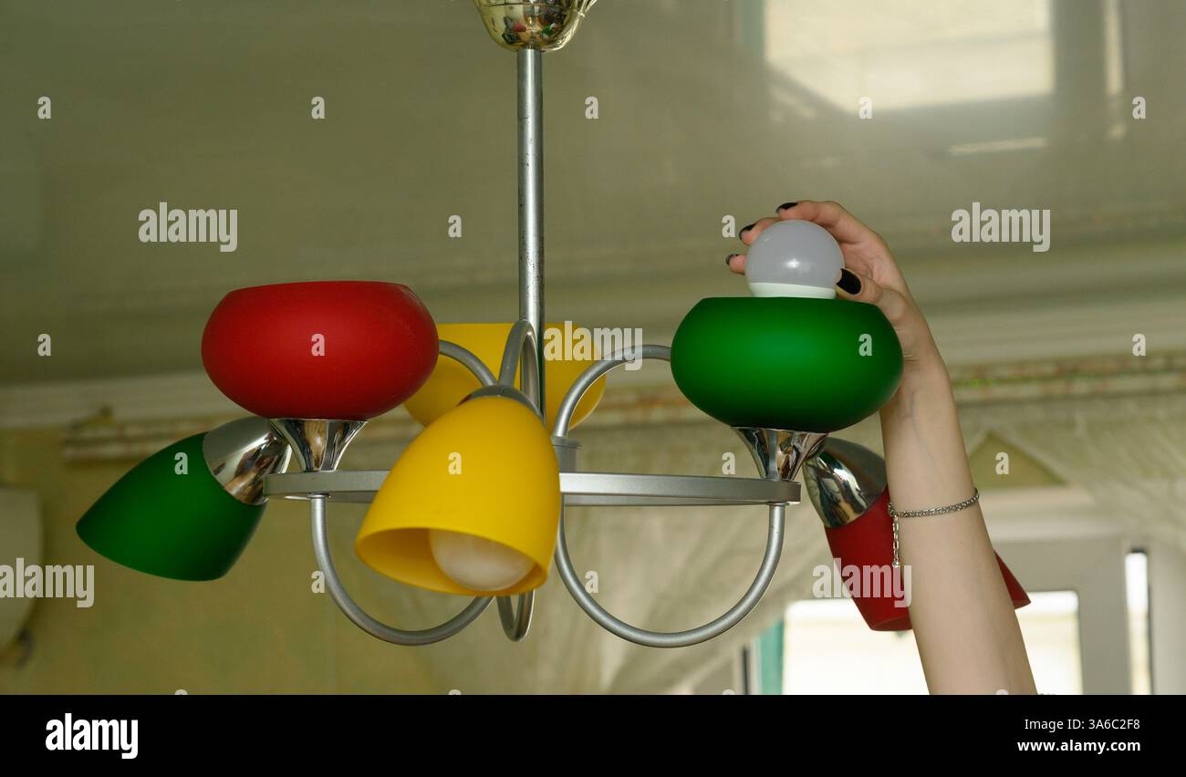 la femme change d'ampoule dans son plafonnier de maison. femme démontre la simplicité de passer à l'éclairage à économie d'énergie. moderne et économe en énergie l Banque D'Images