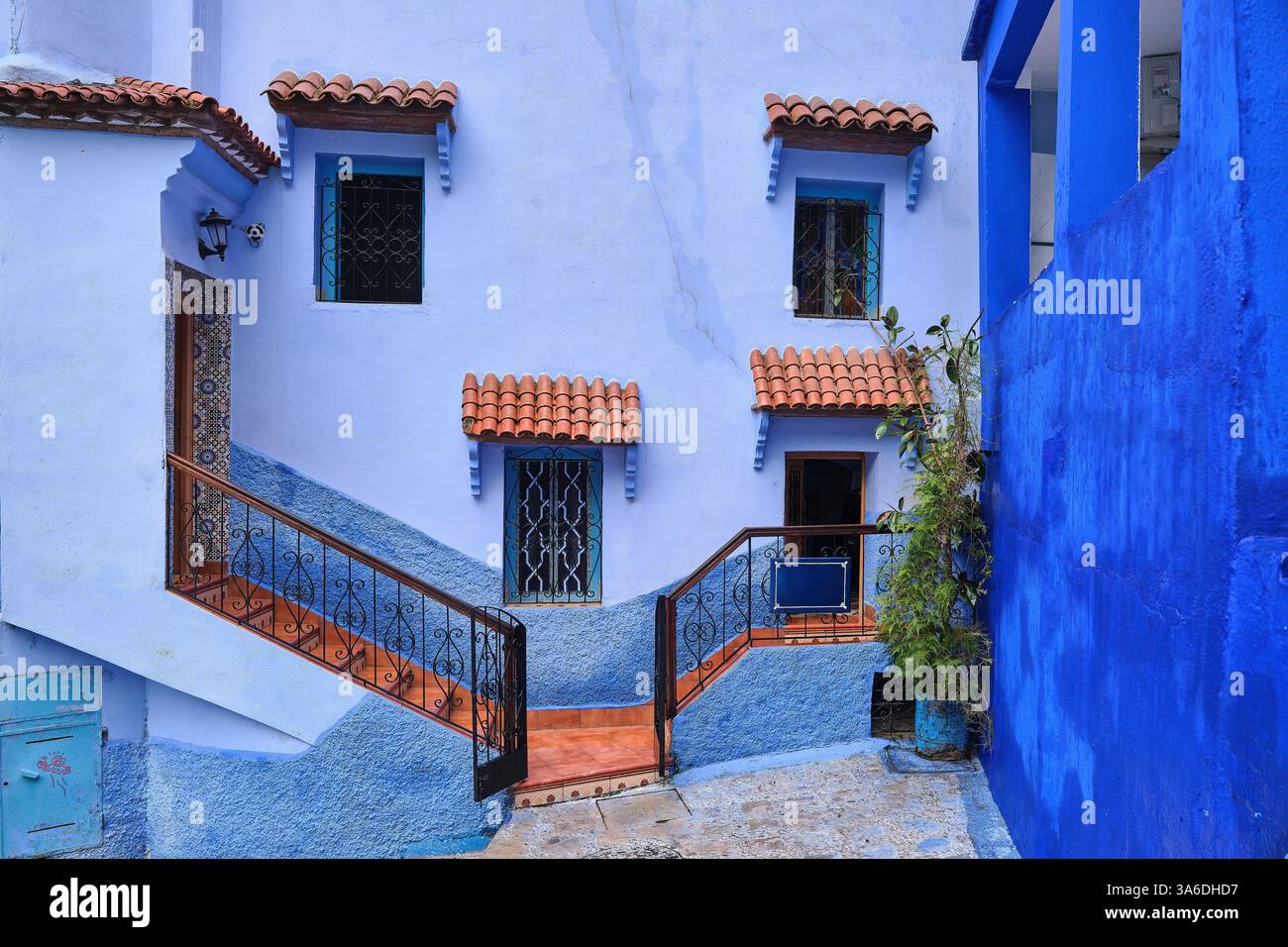 Belle façade de maison de différentes nuances de bleu avec marches orange et auvent de fenêtre carrelé, Chefchaouen, Maroc Banque D'Images