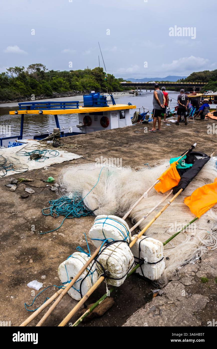 Peruibe, Sao Paulo, 17 janvier 2025. Scène de port de pêche à Peruíbe, état de Sao Paulo. Les filets colorés, les bateaux et la toile de fond de la forêt atlantique capturent t Banque D'Images