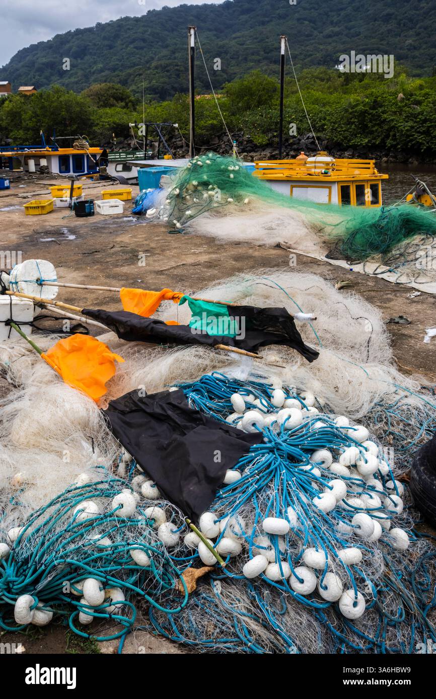 Peruibe, Sao Paulo, 17 janvier 2025. Scène de port de pêche à Peruíbe, état de Sao Paulo. Les filets colorés, les bateaux et la toile de fond de la forêt atlantique capturent t Banque D'Images