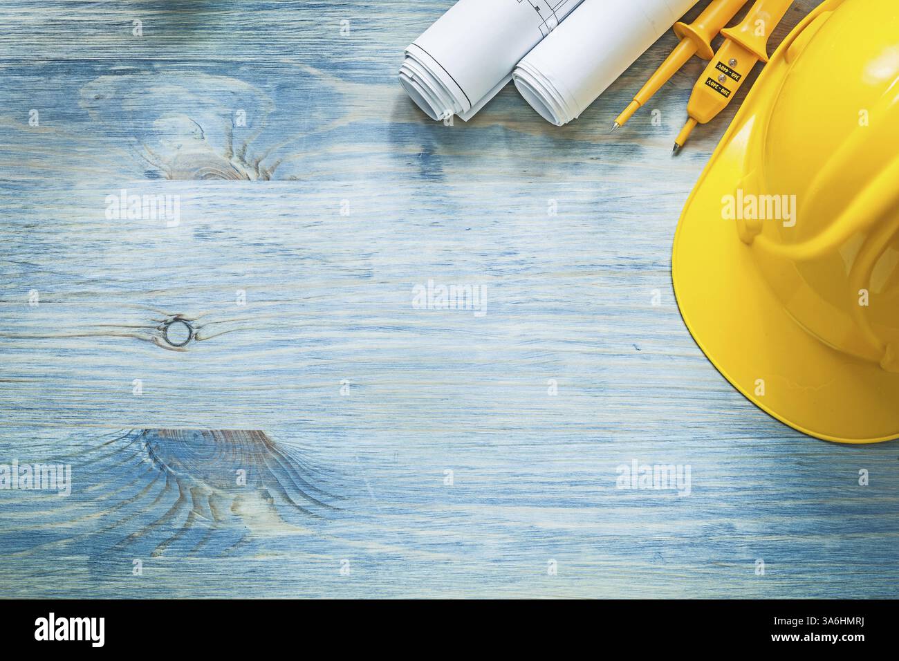 Le casque de construction de testeur électrique a roulé des plans de construction sur le concept d'électricité de planche en bois Banque D'Images