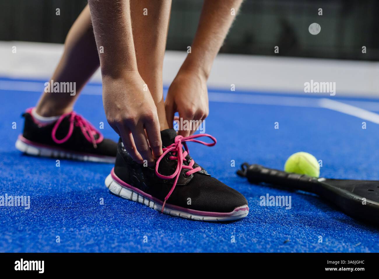 Nouer des lacets sur le court, se préparer au match de padel tennis avec raquette à proximité Banque D'Images