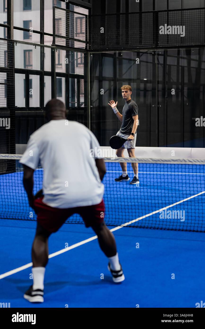 Deux hommes jouant au padel sur court bleu, concentrés et compétitifs Banque D'Images