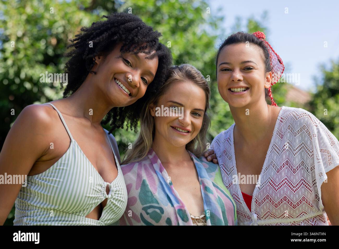Souriant diverses amies féminines profitant d'une journée ensoleillée au bord de la piscine, embrassant les vibrations estivales Banque D'Images