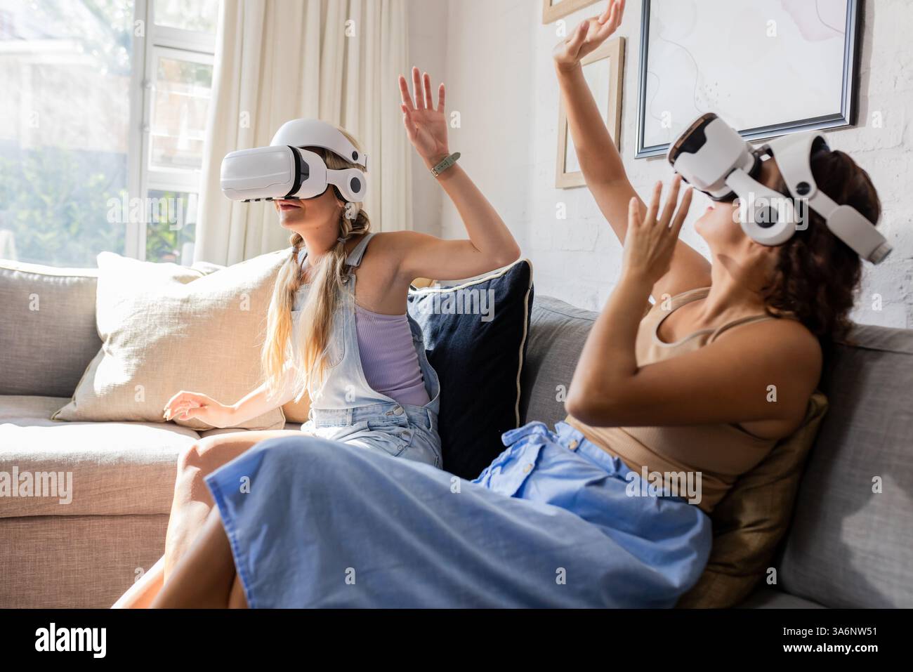 Les femmes appréciant le jeu de réalité virtuelle ensemble sur le canapé, riant et interagissant Banque D'Images