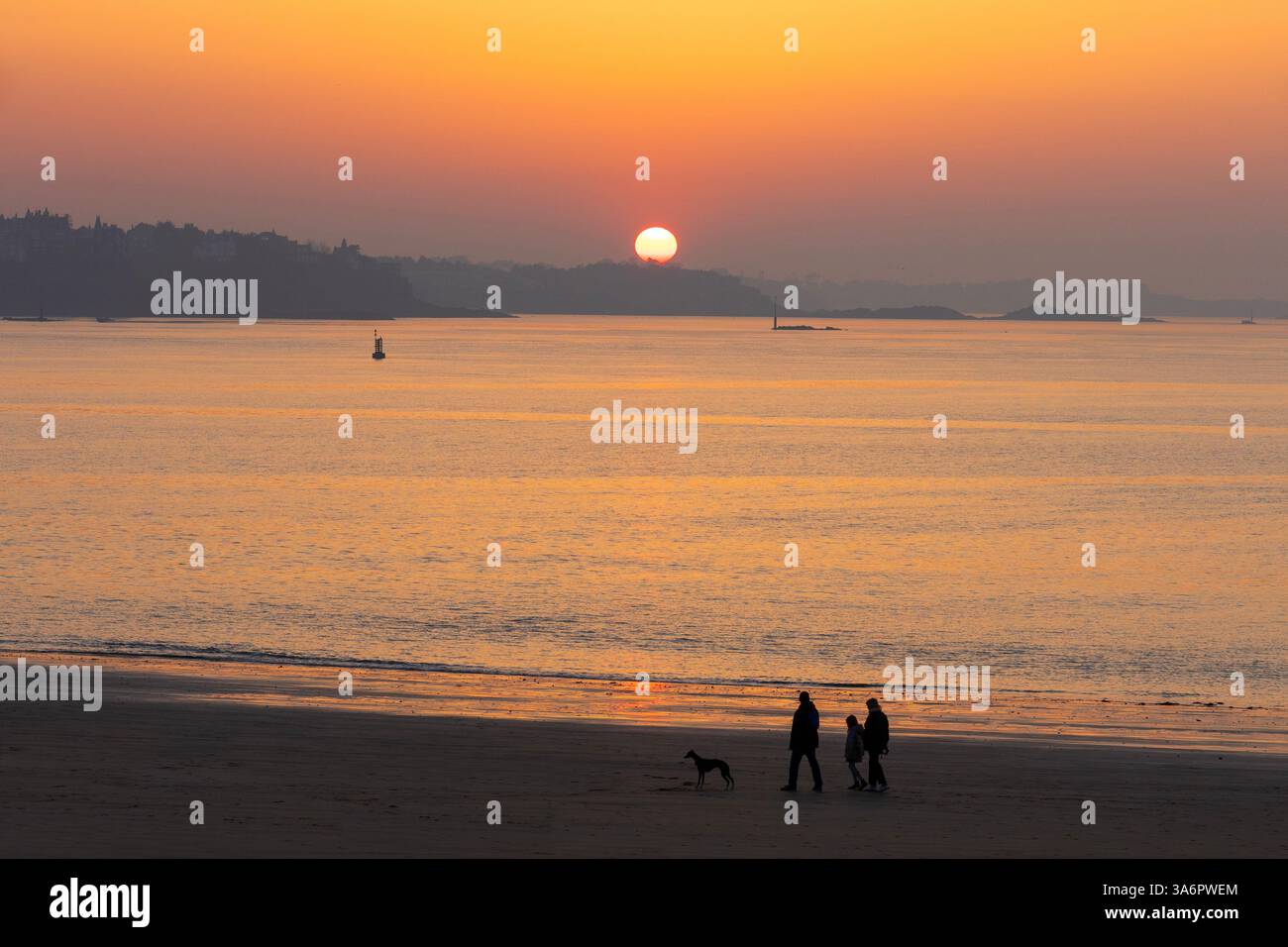 Une famille emmenant son chien se promener à la plage de bon-secours au coucher du soleil à Saint-Malo (Ille-et-Vilaine) en Bretagne Banque D'Images