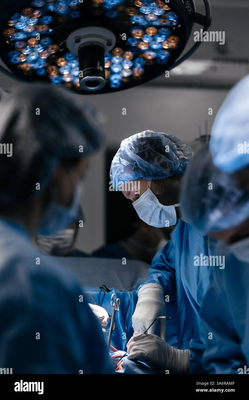 Gros plan sur l'équipe de chirurgie opérant dans un hôpital moderne. Les travailleurs médicaux travaillent en équipe, sauvant la vie du patient en sauvant la chirurgie plastique cardio. Banque D'Images