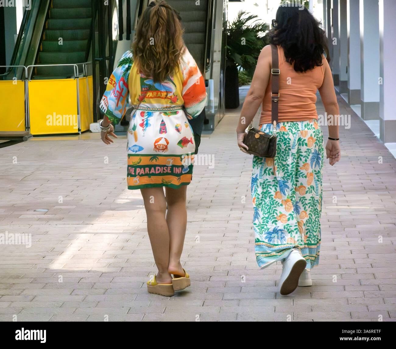 Vue arrière deux femmes en robes colorées marchant dans la rue Banque D'Images