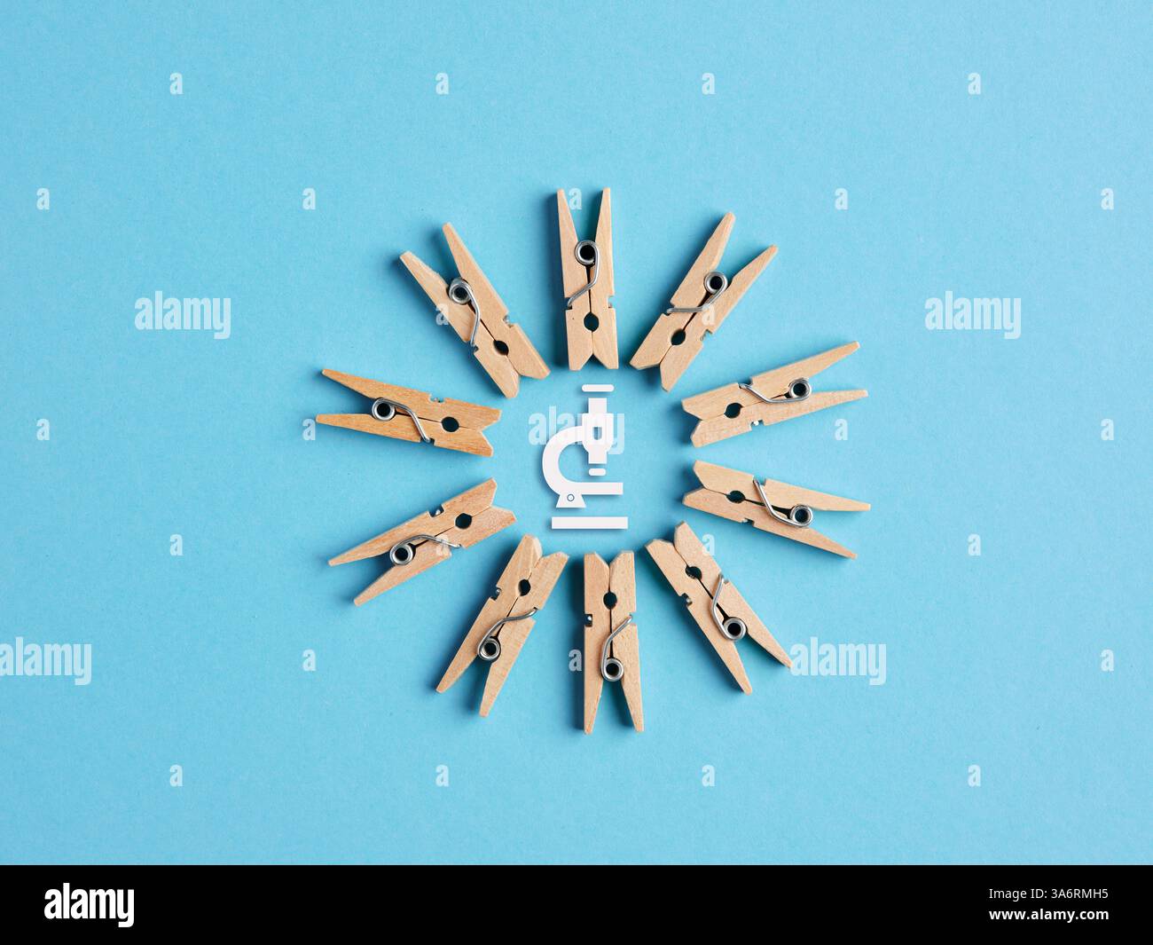 Réflexion collective et brainstorming dans le concept de recherche scientifique. Pinces à linge miniatures en bois formant un cadre circulaire avec symbole de microscope sur bl Banque D'Images