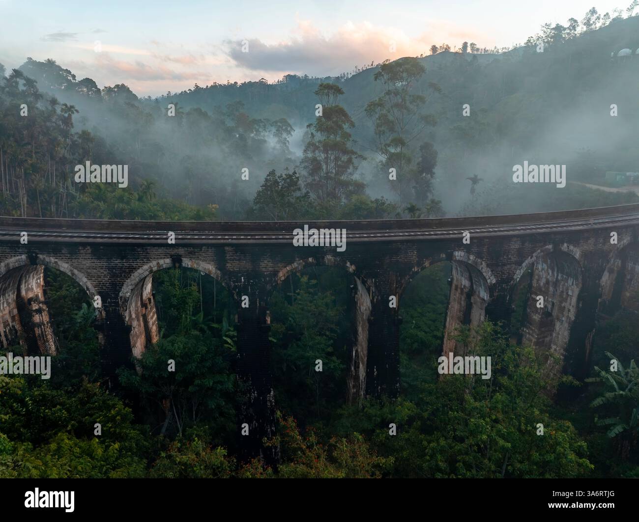 L'emblématique pont Nine Arch près d'Ella, au Sri Lanka, émerge de la brume, entouré d'une jungle tropicale luxuriante, mettant en valeur un mélange d'histoire, de nature, d'an Banque D'Images