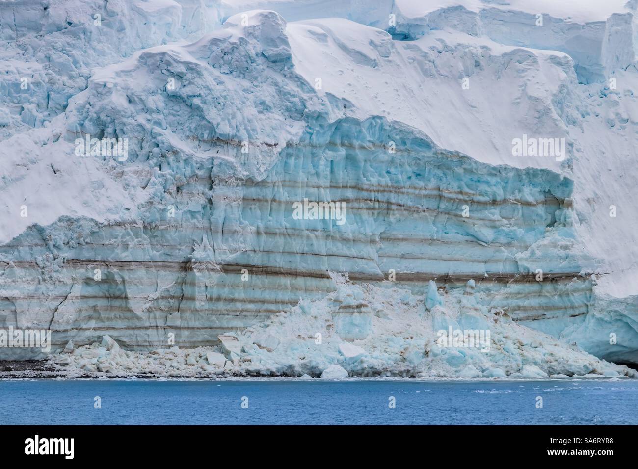 Falaise de glace bleue sur le rivage de la péninsule Antarctique. Océan au premier plan. Banque D'Images