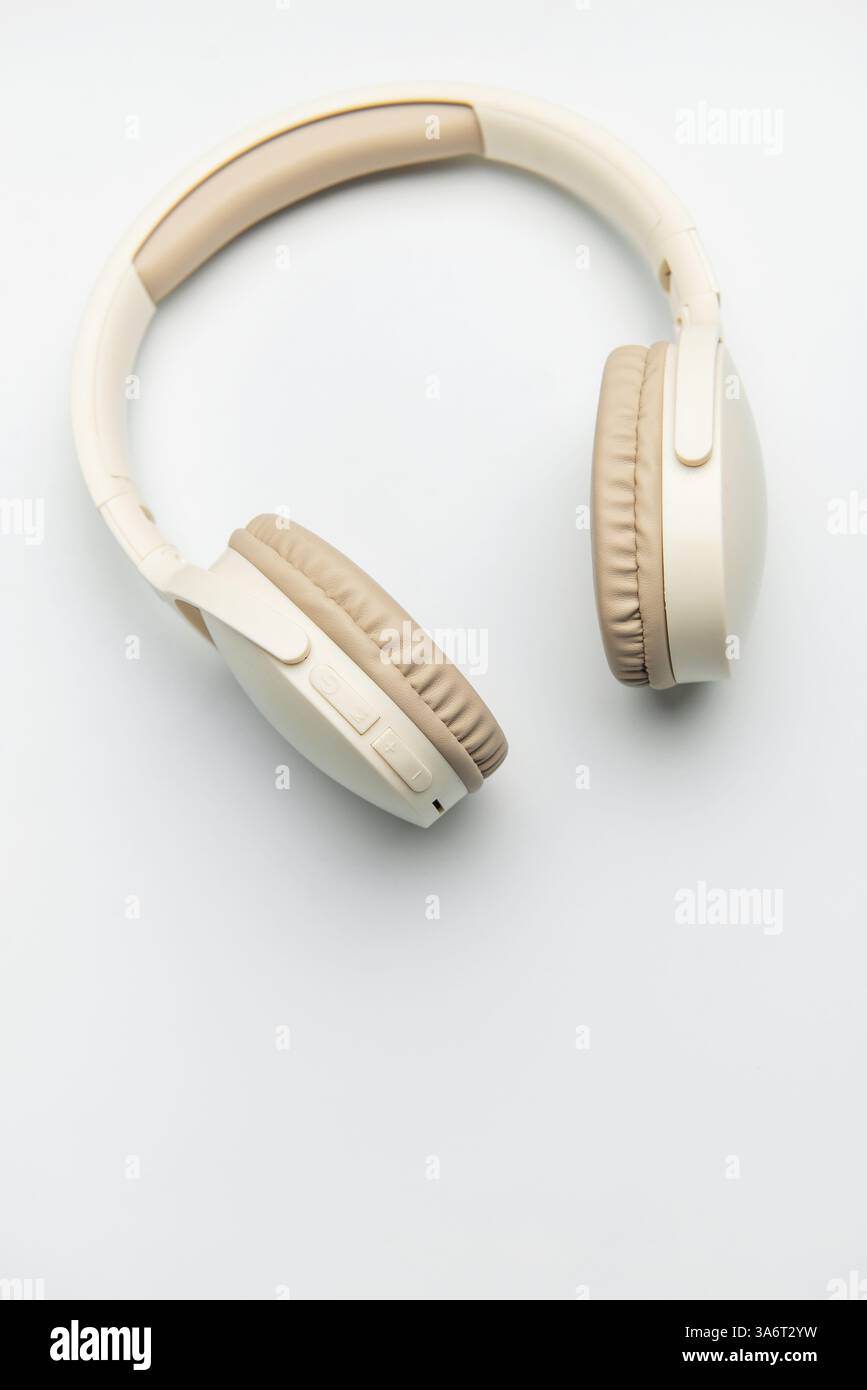 Casque sans fil beige et blanc isolé sur fond blanc, représentant l'écoute de musique, le plaisir de podcast ou la communication audio Banque D'Images