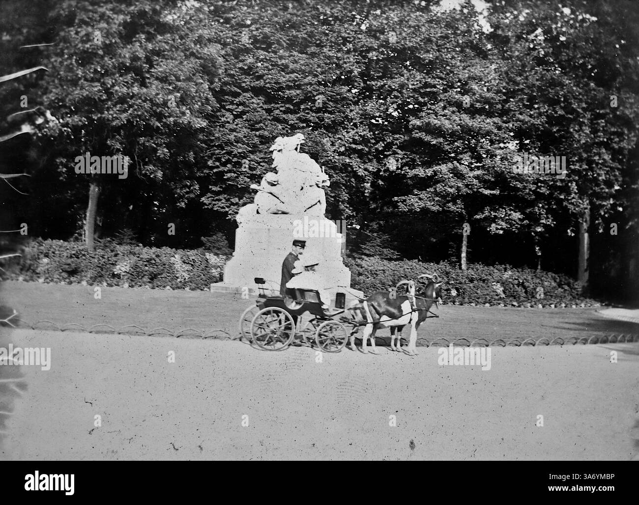 Jardins zoologiques d'Anvers : un chariot tiré par deux béliers. Une dame et un homme, ce dernier probablement un préposé de zoo, sont dans le chariot en passant une statue. D’après une collection de photographies d’une tournée européenne familiale qui s’est déroulée en 1899. Les photographies originales étaient d'environ 3 ½ x 2 ½ pouces et présentent une vue intéressante des coutumes, des modes et de l'histoire sociale de la fin de la période victorienne. Banque D'Images