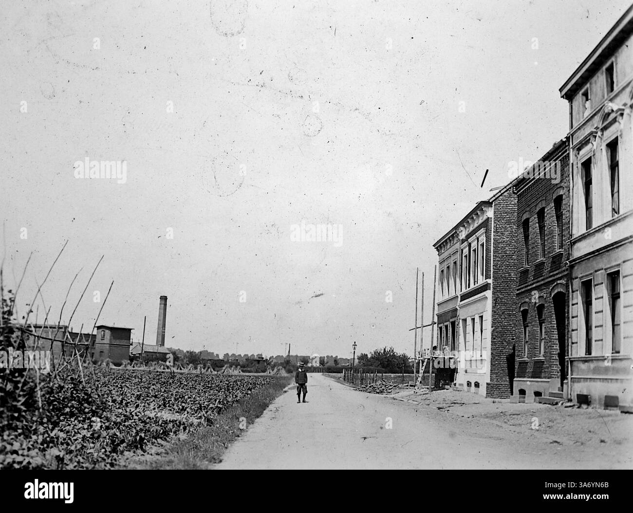 Maisons résidentielles et le paysage environnant à Linn, un quartier historique de la ville de Krefeld, situé dans l'état de Rhénanie du Nord-Westphalie, Allemagne. Un jeune homme est debout dans la rue et au loin une grande cheminée industrielle peut être vue. D’après une collection de photographies d’une tournée européenne familiale qui s’est déroulée en 1899. Les photographies originales étaient d'environ 3 ½ x 2 ½ pouces et présentent une vue intéressante des coutumes, des modes et de l'histoire sociale de la fin de la période victorienne. Banque D'Images