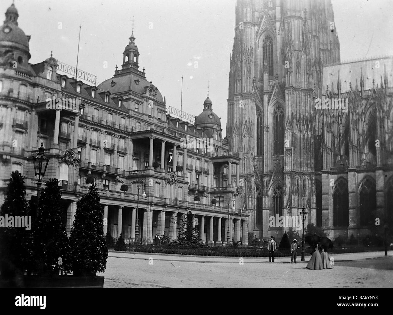Un groupe de personnes à côté de l'hôtel Dom, près de la cathédrale de Köln, en Allemagne, connue sous le nom de Cologne en anglais. C'est une ville de l'ouest de l'Allemagne située le long du Rhin. D’après une collection de photographies d’une tournée européenne familiale qui s’est déroulée en 1899. Les photographies originales étaient d'environ 3 ½ x 2 ½ pouces et présentent une vue intéressante des coutumes, des modes et de l'histoire sociale de la fin de la période victorienne. Banque D'Images