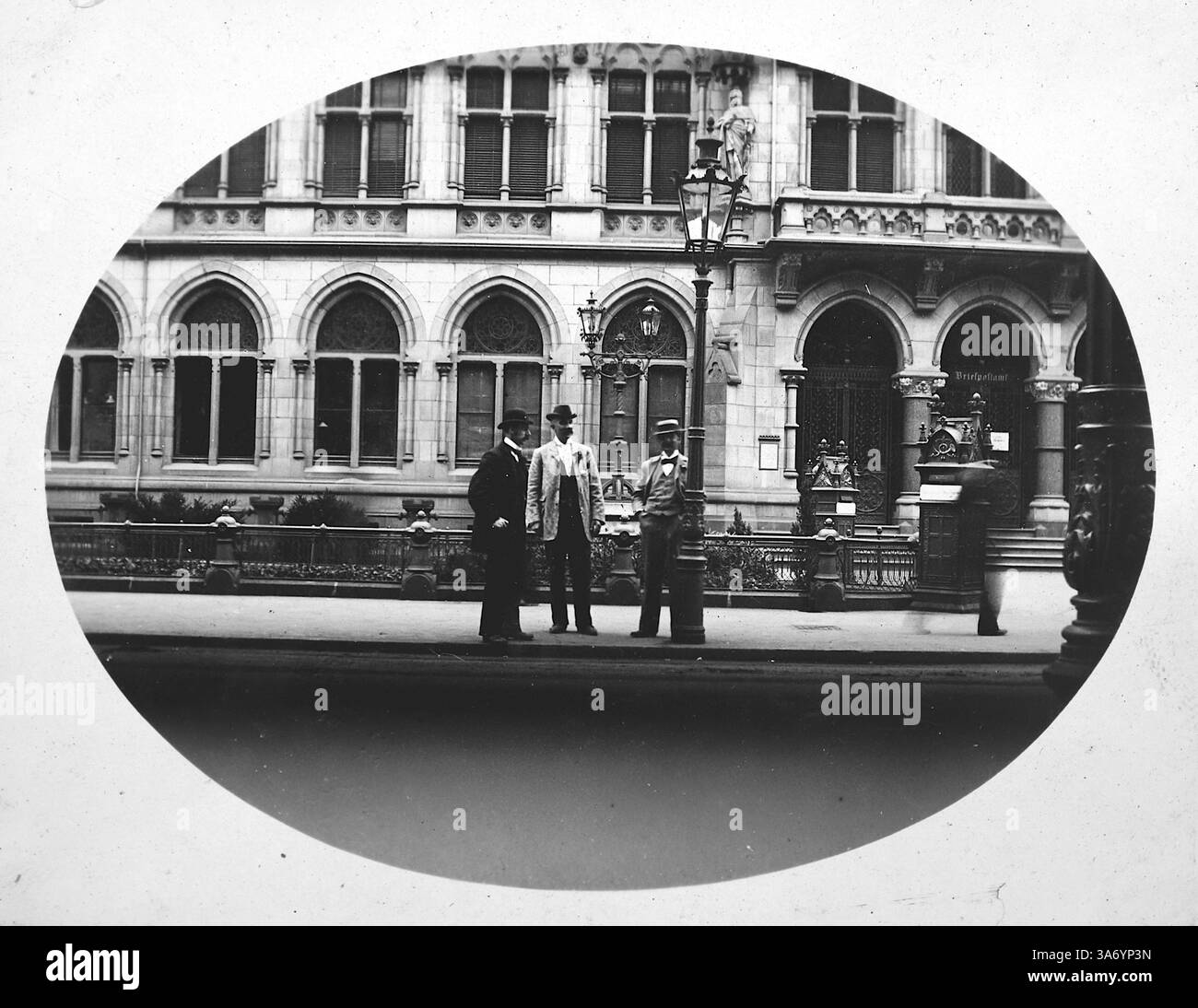 Un groupe de messieurs portant des chapeaux et debout à côté d'un lampadaire devant le bâtiment de la poste à Cologne, en Allemagne. D’après une collection de photographies d’une tournée européenne familiale qui s’est déroulée en 1899. Les photographies originales étaient d'environ 3 ½ x 2 ½ pouces et présentent une vue intéressante des coutumes, des modes et de l'histoire sociale de la fin de la période victorienne. Banque D'Images