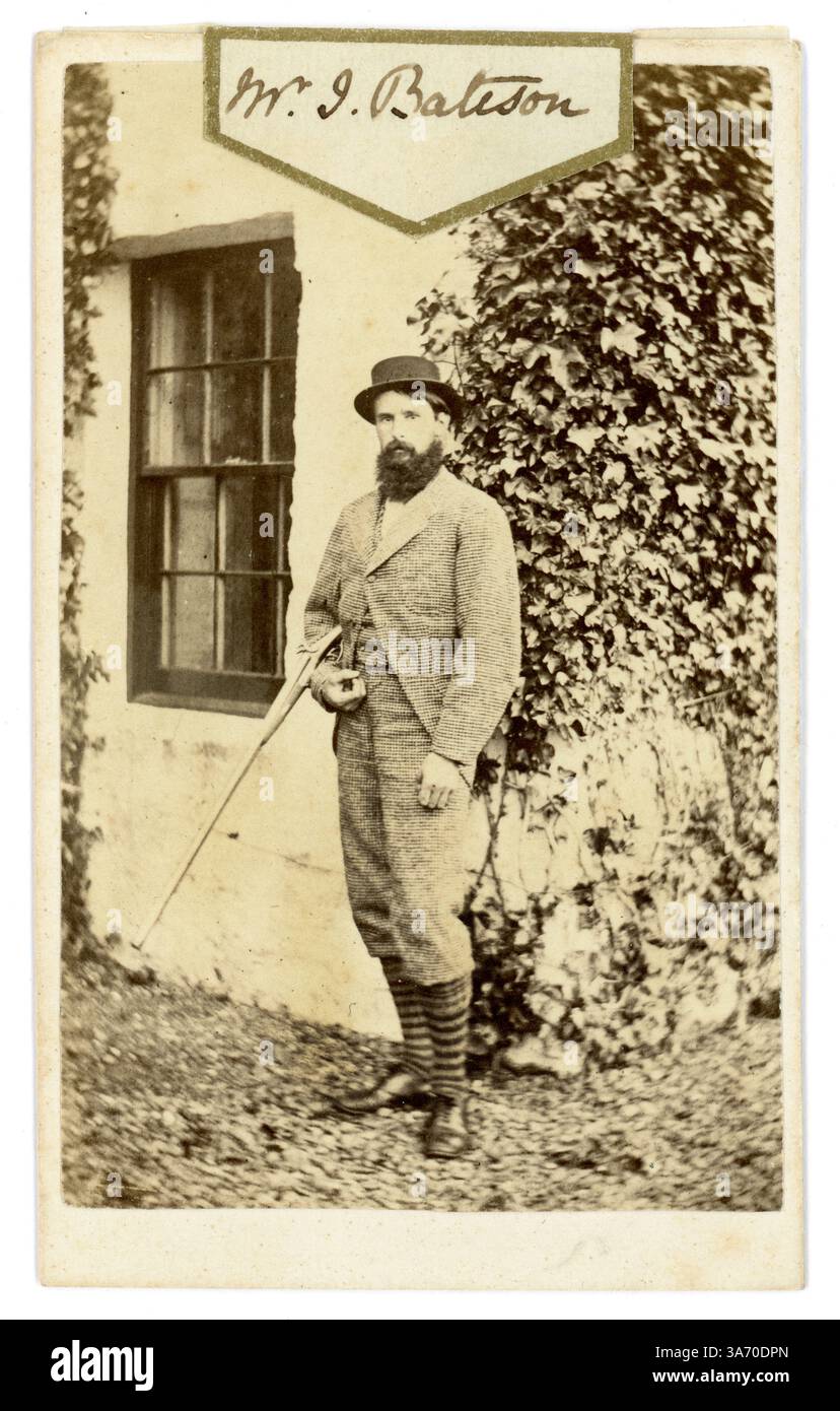 Carte de visite victorienne originale (carte de visite ou CDV) avec une étiquette pour l'album de cartes de visite, d'un jeune homme victorien barbu attrayant, gentleman victorien, appelé M. John Bateson, portant des vêtements de sport de pays de gentry débarqué, posant pour une photographie à l'extérieur de sa maison, tenant un fusil de chasse. D'après une collection de la famille Arkwright, Hampton court Castle Hereford, photographié par Marcus Ward & Co 13 Donegall place, Belfast c1867 Banque D'Images